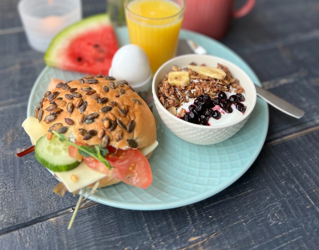 Frukosttallrik med fralla, yoghurt med granola och blåbär, kokt ägg, vattenmelon och juice